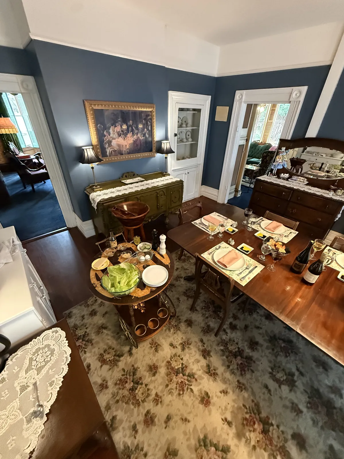 Victorian dining room at the Shaw House Inn with a table set for dinner, wine glasses, and a salad cart beside it